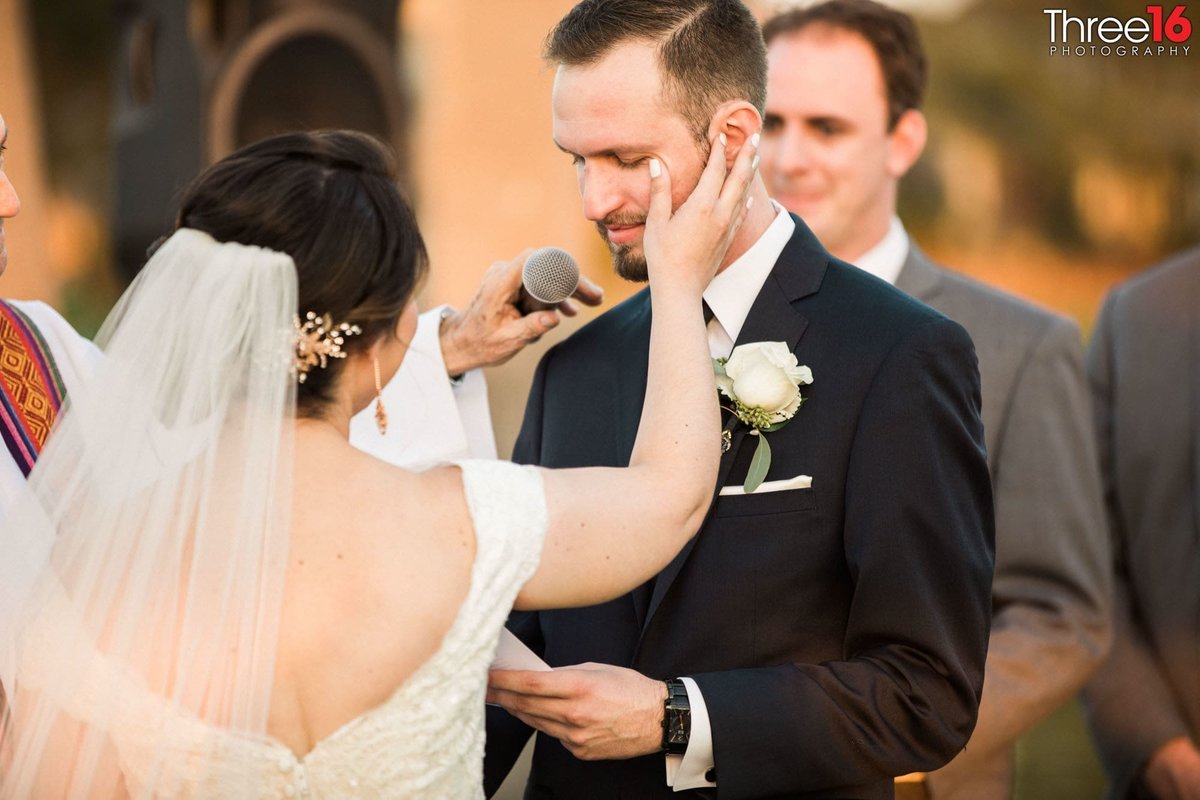 Bride wipes a tear from her Groom's cheek as he reads his wedding vows