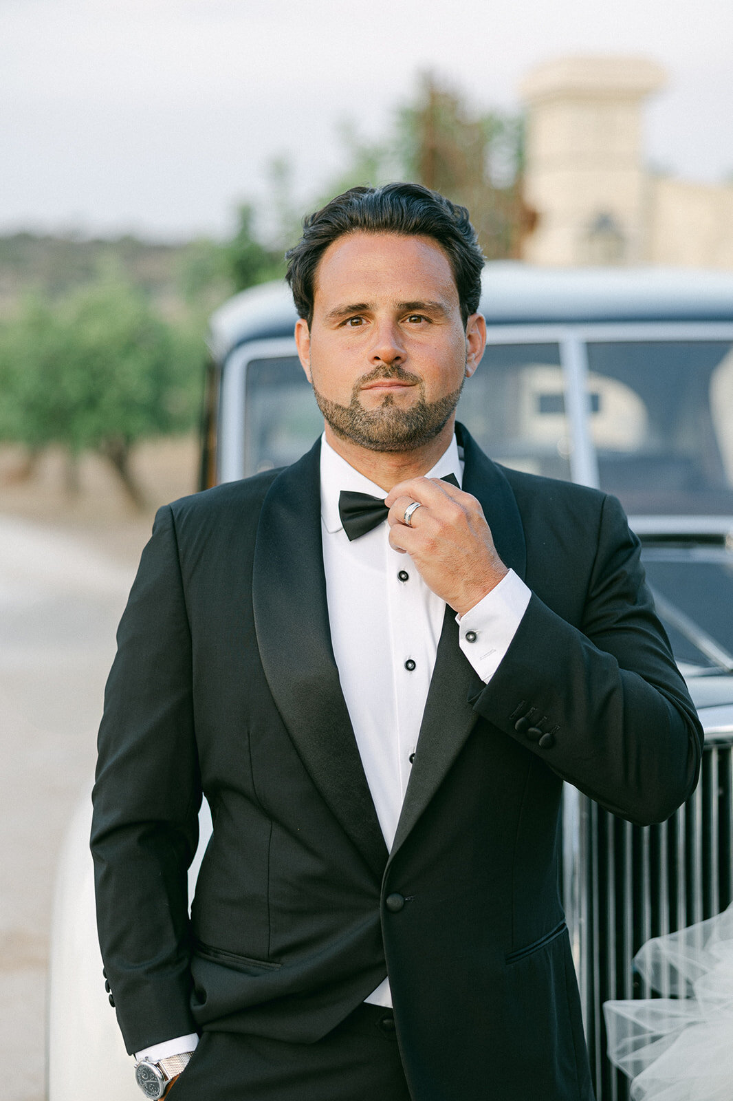 a groom adjusting his bow tie