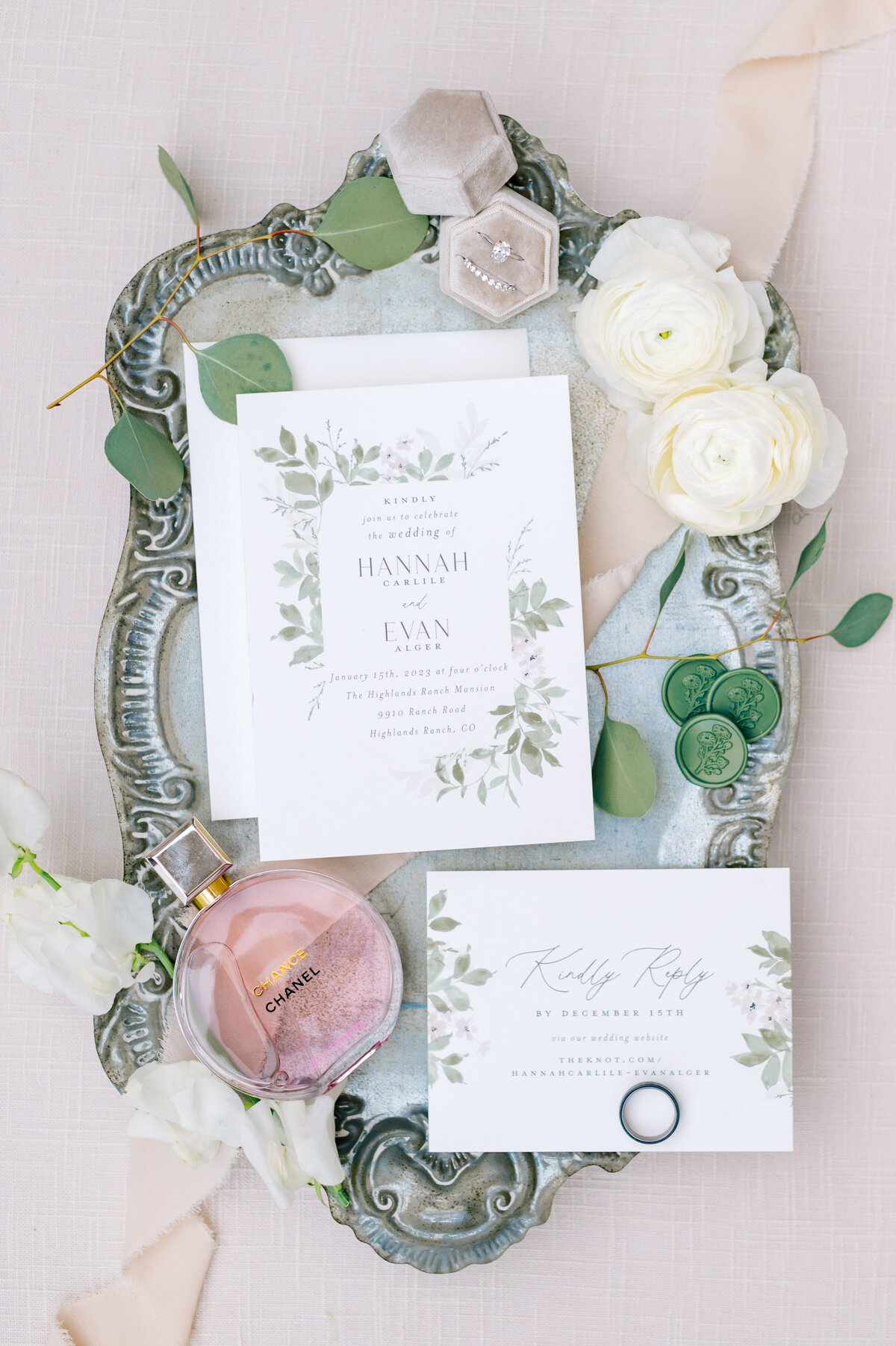 flat lay on of wedding invitations with sage green accents and chanel perfume at the highlands ranch mansion by colorado wedding photographer kari joy
