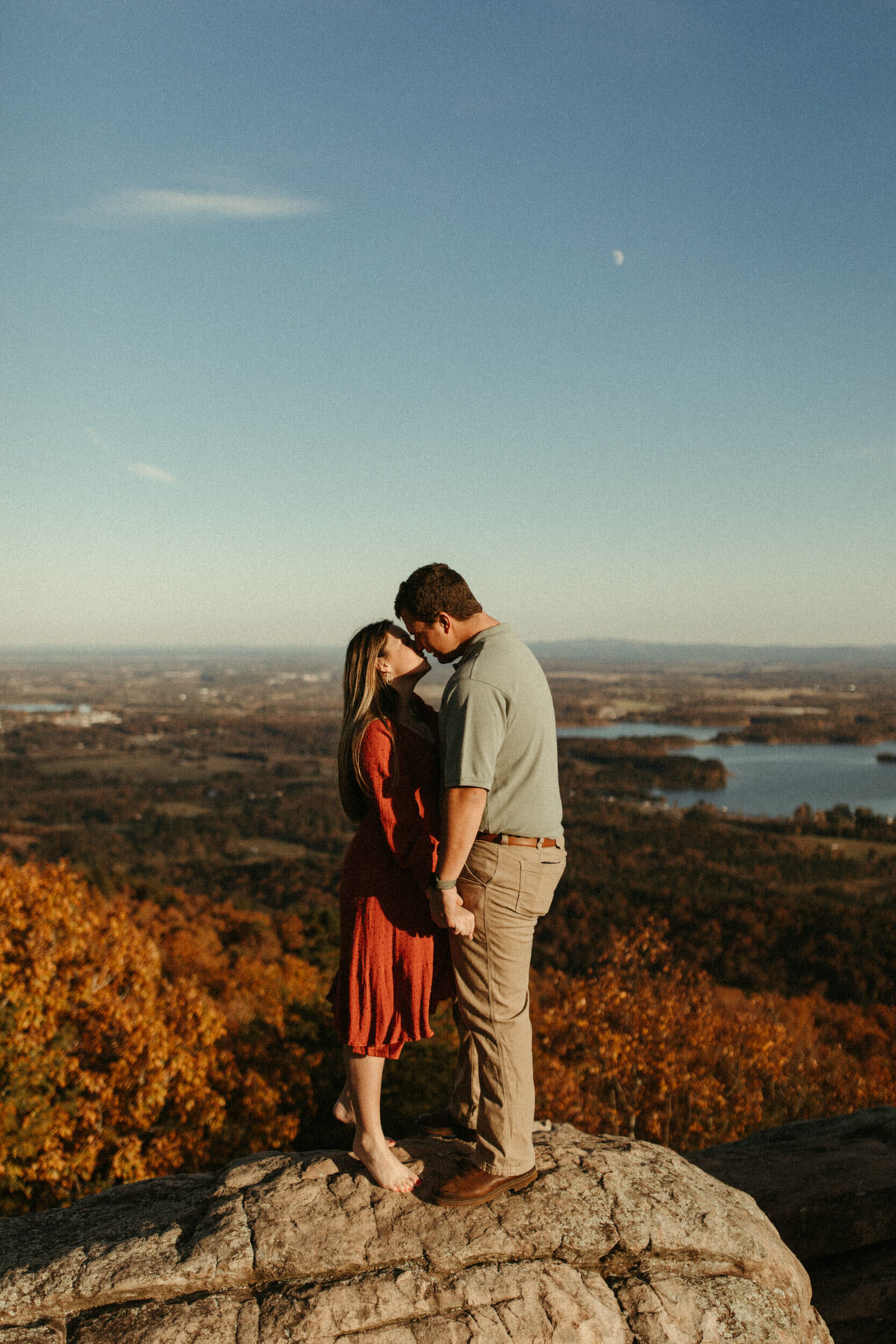 Couple kissing and standing on a rocky overlook on a fall evening