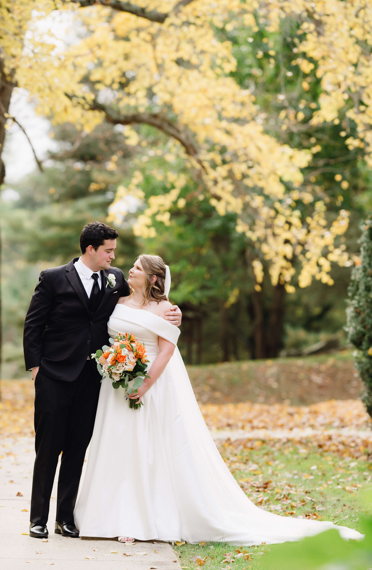 Virginia wedding photographer captures bride and groom on a path together with groom wrapping his arm around his bride and she looks up to him in love at richmond wedding venues
