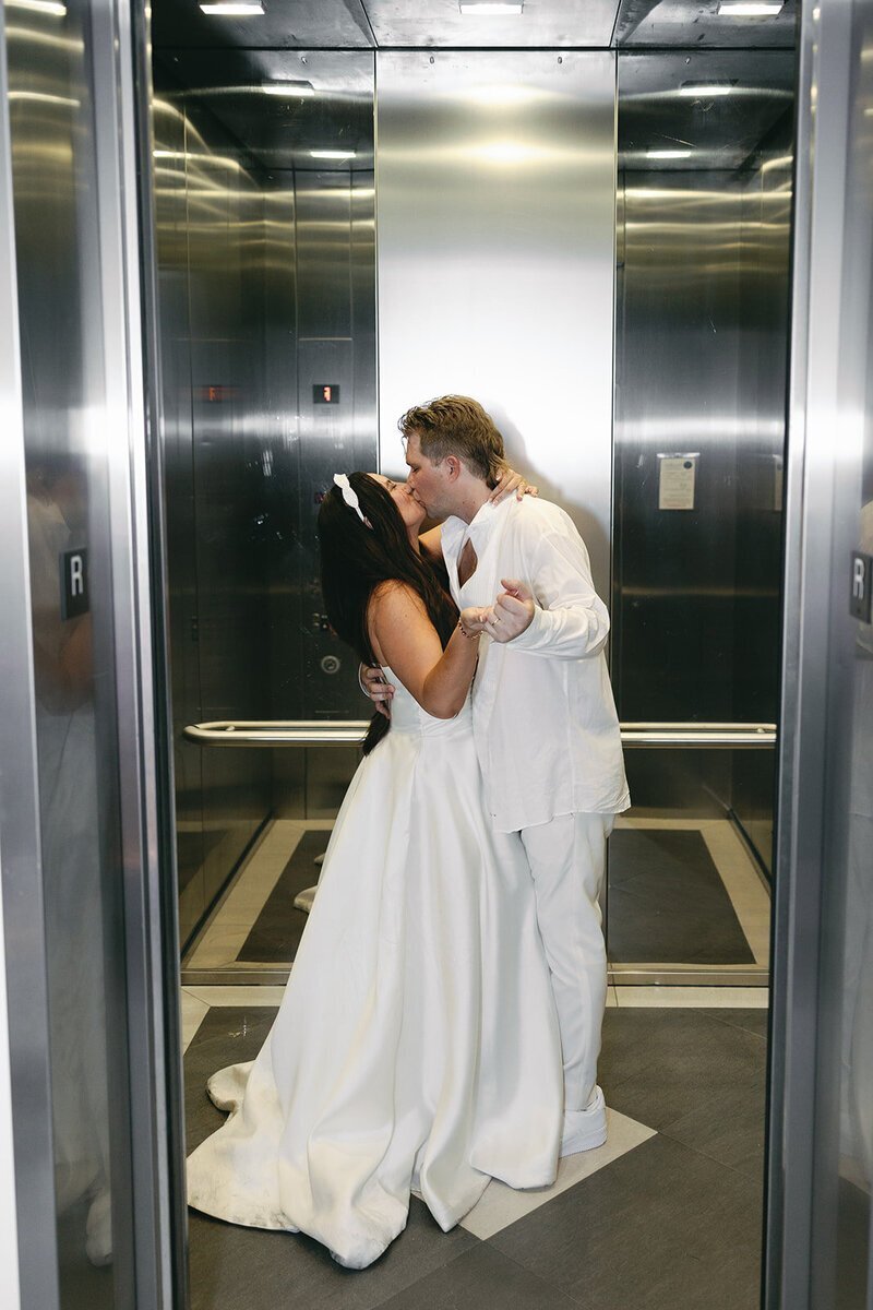 bride and groom kissing in elevator at the penthouse at riverside wharf​