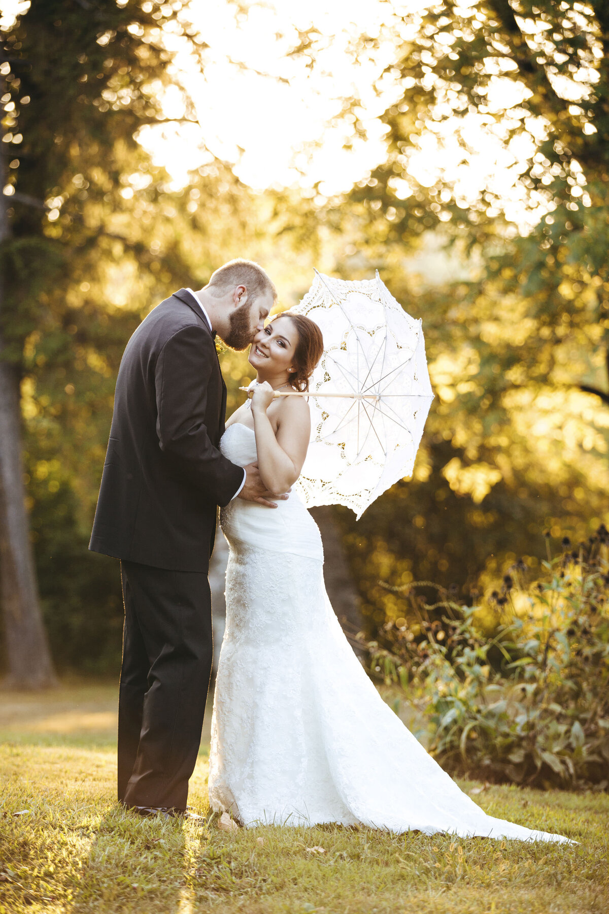 the-inn-at-barley-sheaf-wedding-groom-kissing-bride-on-cheek-with-white-umbrella-sunset-holicong-pennsylvania