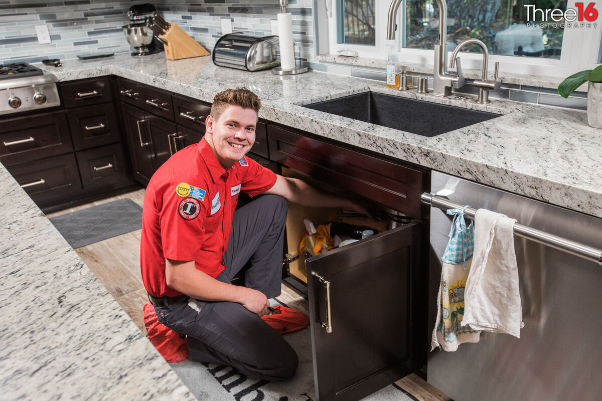 Plumber smiles before going under the sink to fix an issue