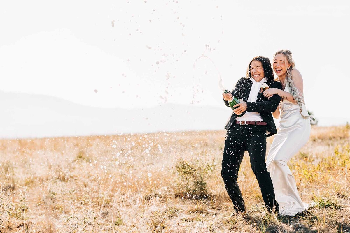 Missoula same sex wedding couple popping champagne cork, Blue Mountain, Missoula