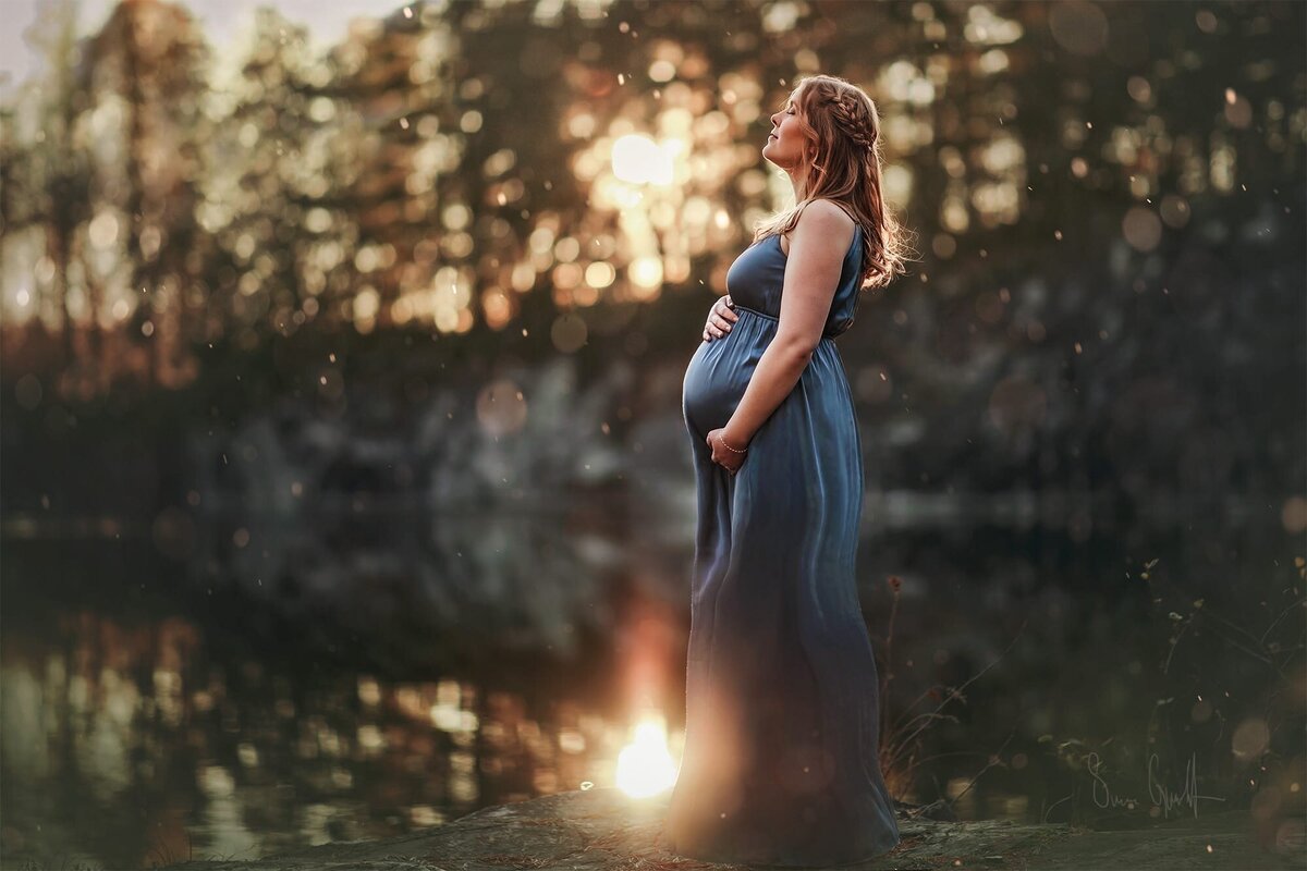 drömmig gravidbild av en gravid kvinna i blå långklänning ute i naturen