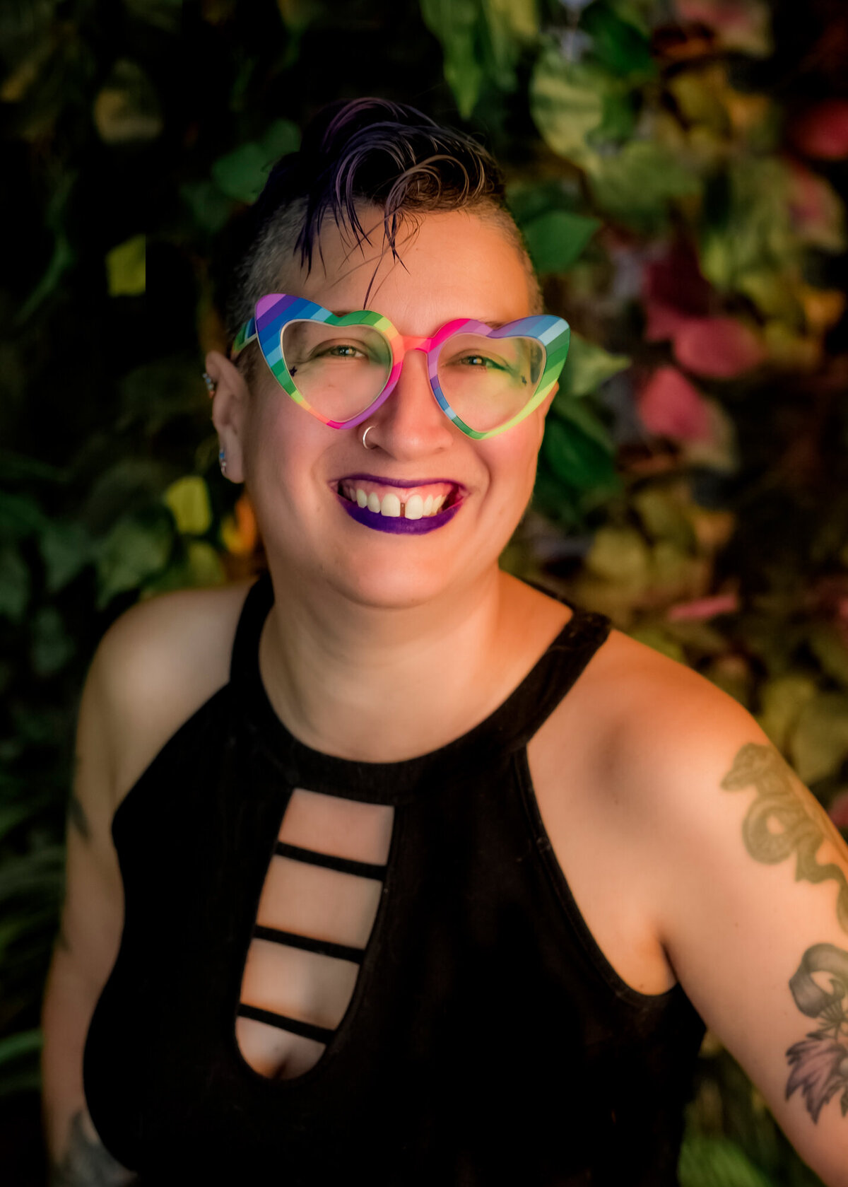 They/them headshot client wearing rainbow glasses & smiling at the camera