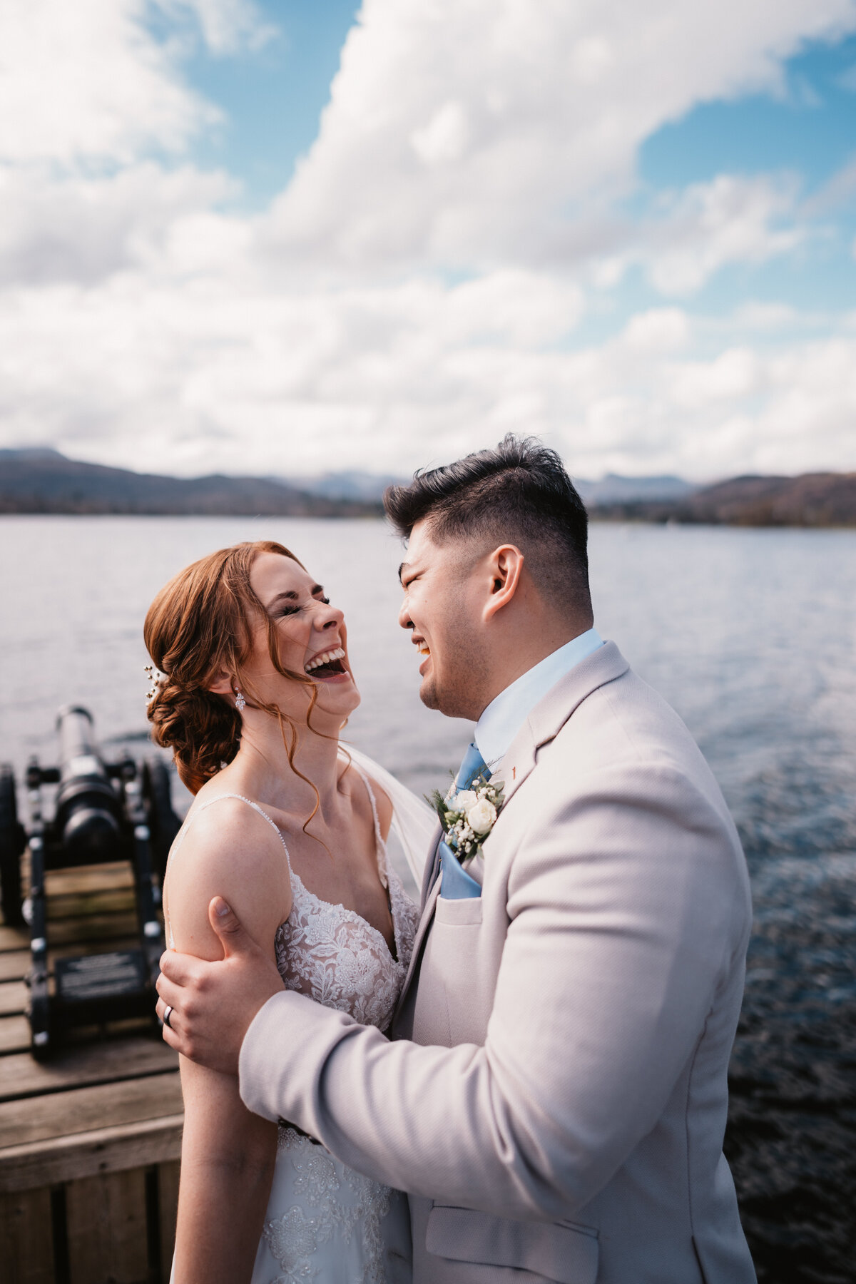 Bride and groom laughing together by the lakeside at Low Wood Bay Resort & Spa, Lake District, during a romantic elopement.