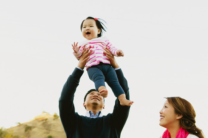 Parents hold their child in the air smiling in a candid shot