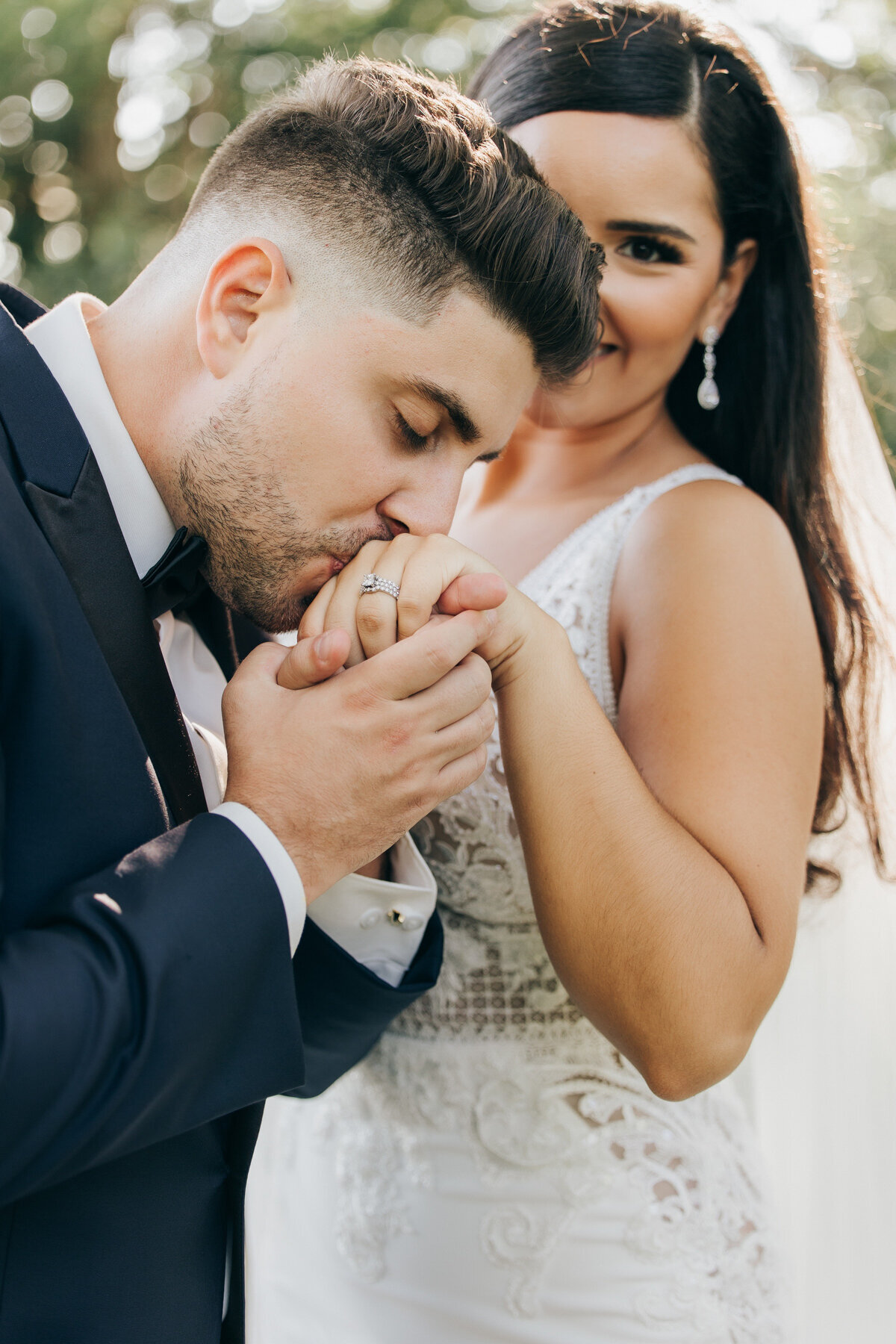 A groom kissing his bride's left hand