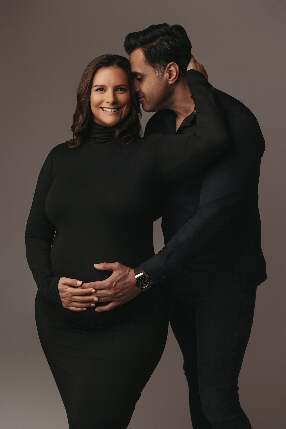 pregnant couple posing for studio maternity photographer in phoenix in all black outfits