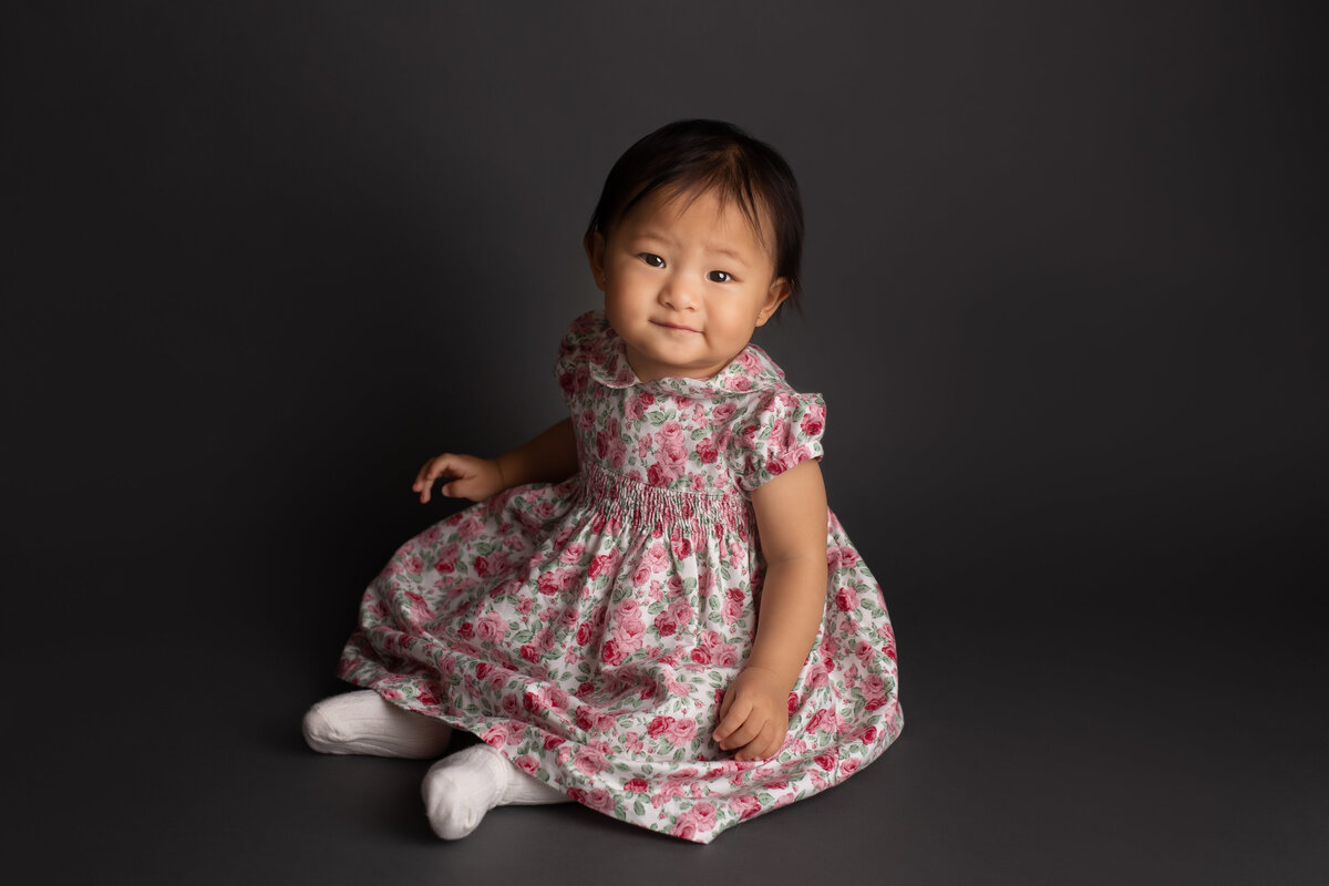 Baby sitting posing for photo in floral dress
