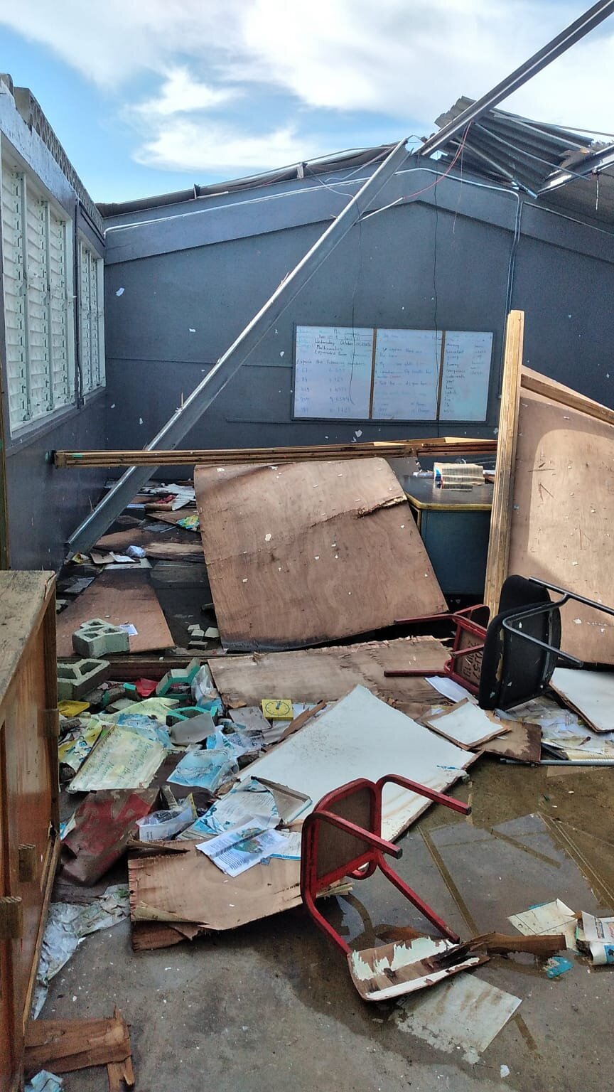 Classroom area with major roof damage and scattered debris after the storm.