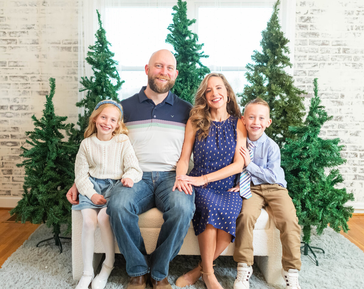 family sitting on sofa in front of christmas trees