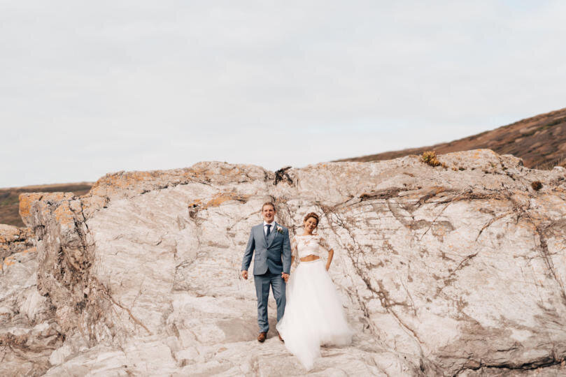 A bride and groom standing in front of a white stone cliff