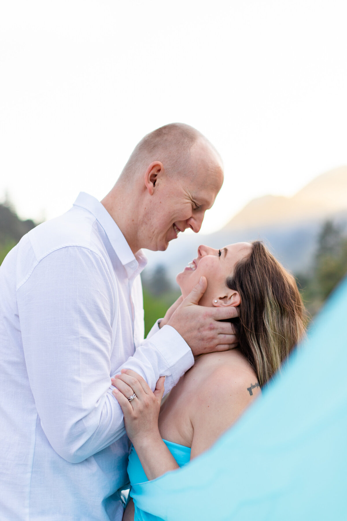 couple smiles with teal maternity dress