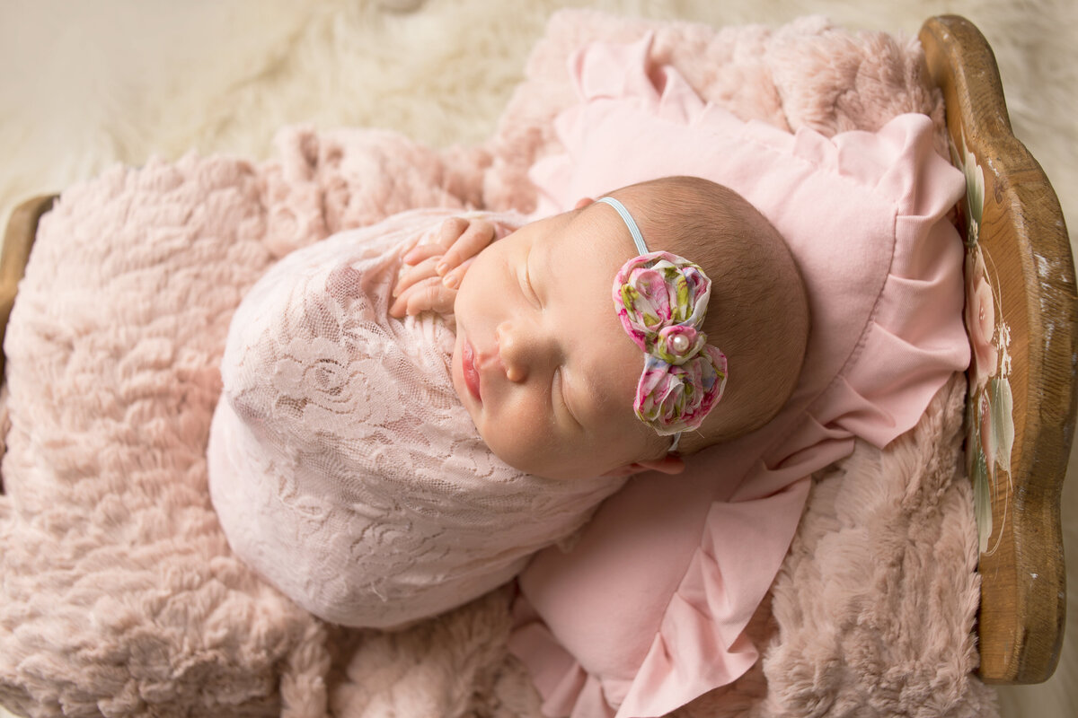 Newborn baby girl wrapped in pink lace wrap sleeping during newborn photoshoot in Mount Juliet tennessee photography studio