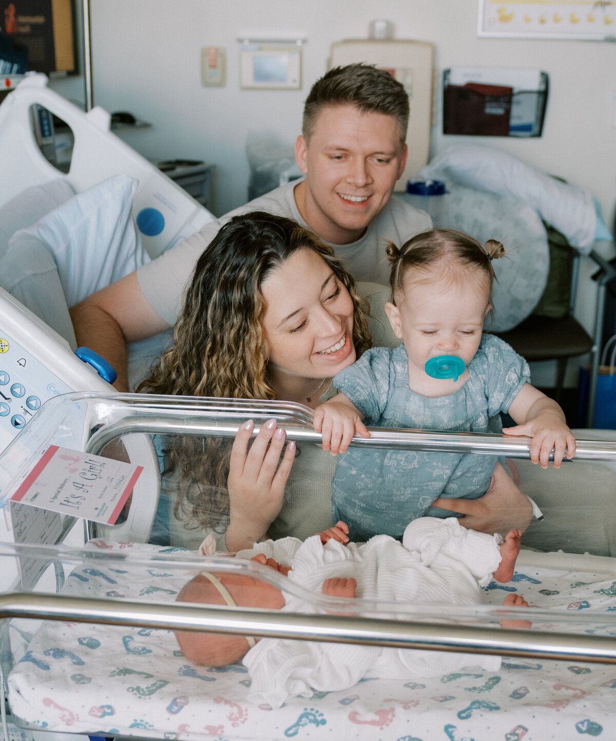 newborn in hospital bassinet with family