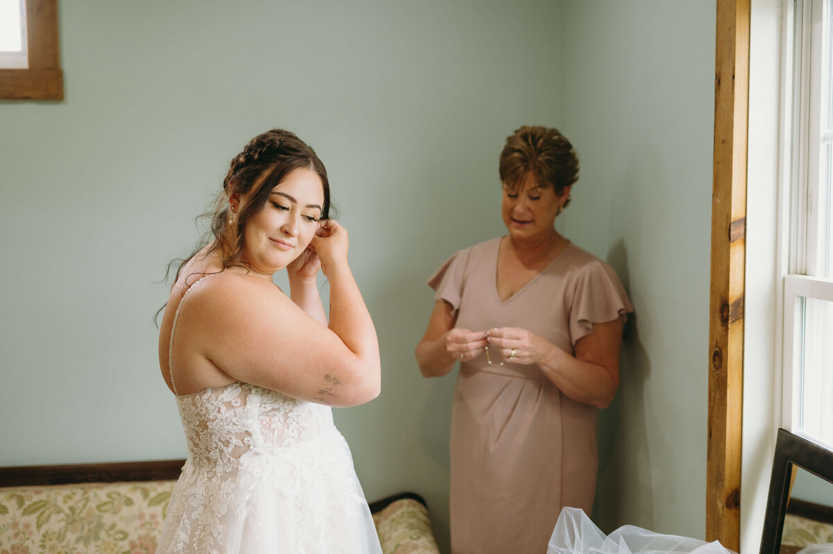 mother of the bride helping the bride with her jewelry in a bridal suite of Sunny Slope Farms