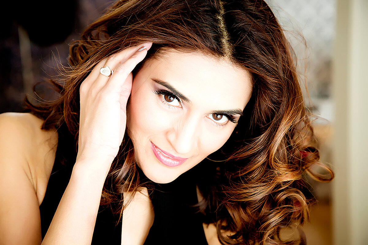 A female dating portrait client with her hand in her hair, smiling at the camera