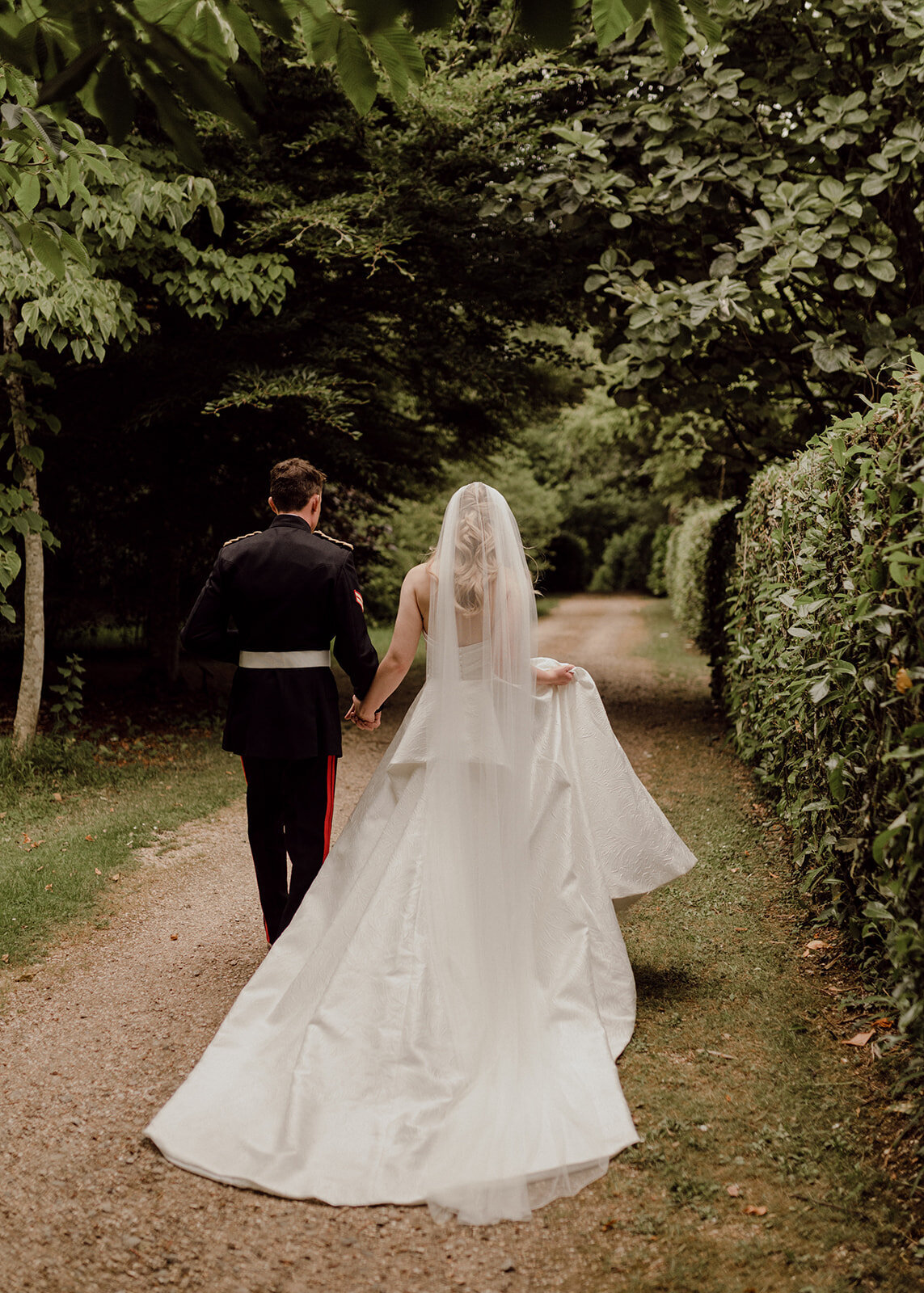 Bride and groom walking down garden path