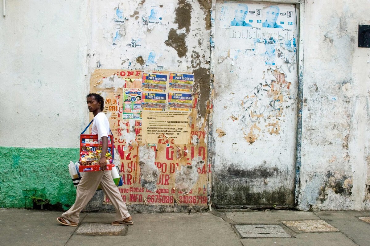 A man walks by an old wall with treats to sell. Editorial photo of a Cartagena street scene