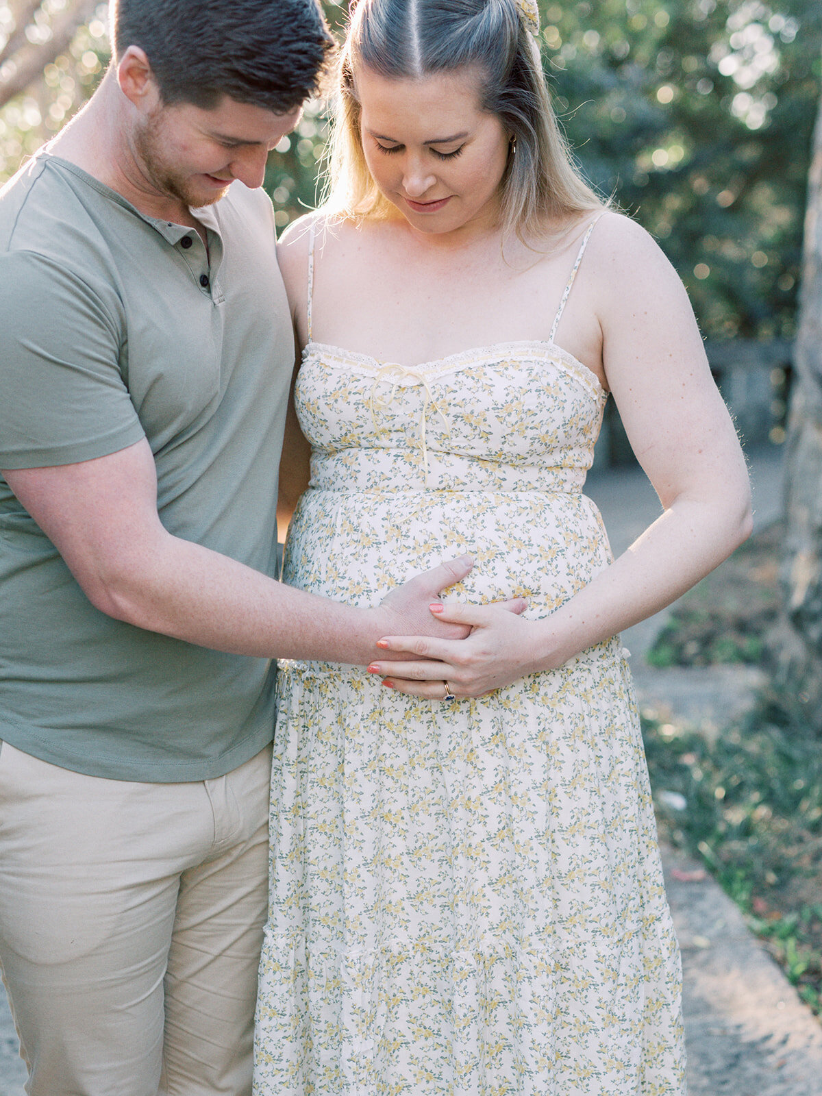A couple looking down at and holding a woman's pregnancy bump at a Richmond maternity photography session by Katie Stansfield Photography.