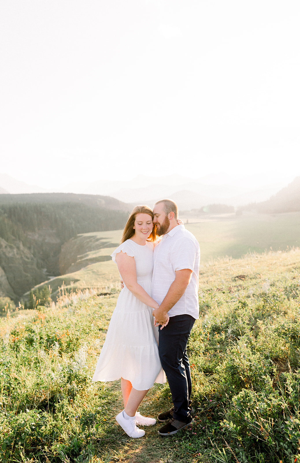 Engaged couple holds hands at golden hour in front of a picturesque valley in the Rocky Mountains
