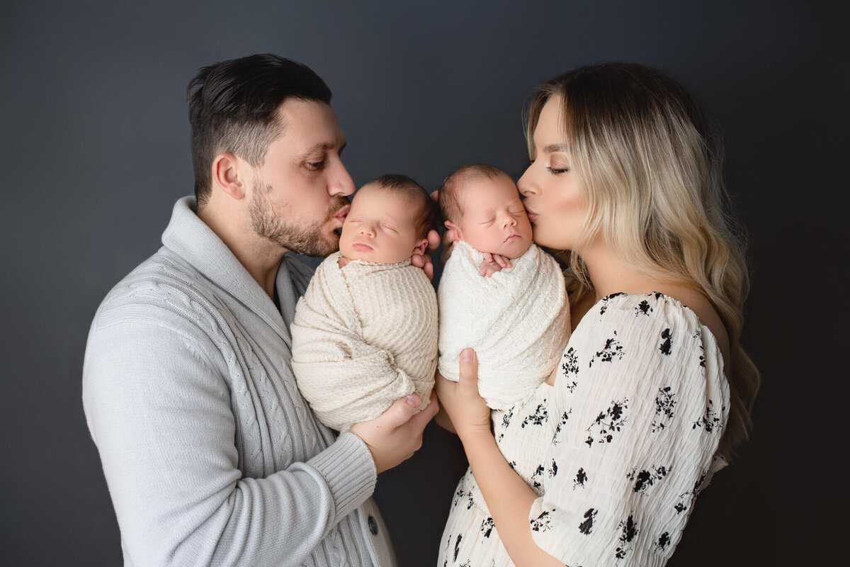 parents give newborn twins kisses for their photo session in Hamilton