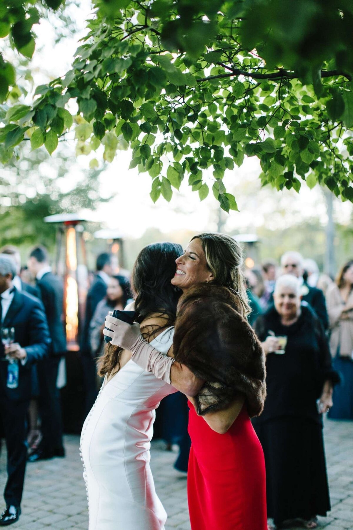 Bride embraces her Mother after a Welcome Toast at a Luxury Michigan Lakefront Golf Club Wedding.