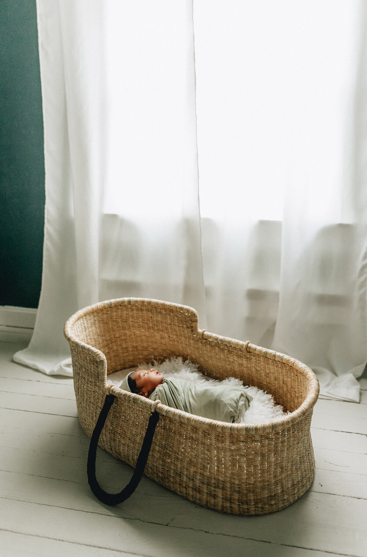 Infant photographer capturing a newborn baby sleeping in crib.