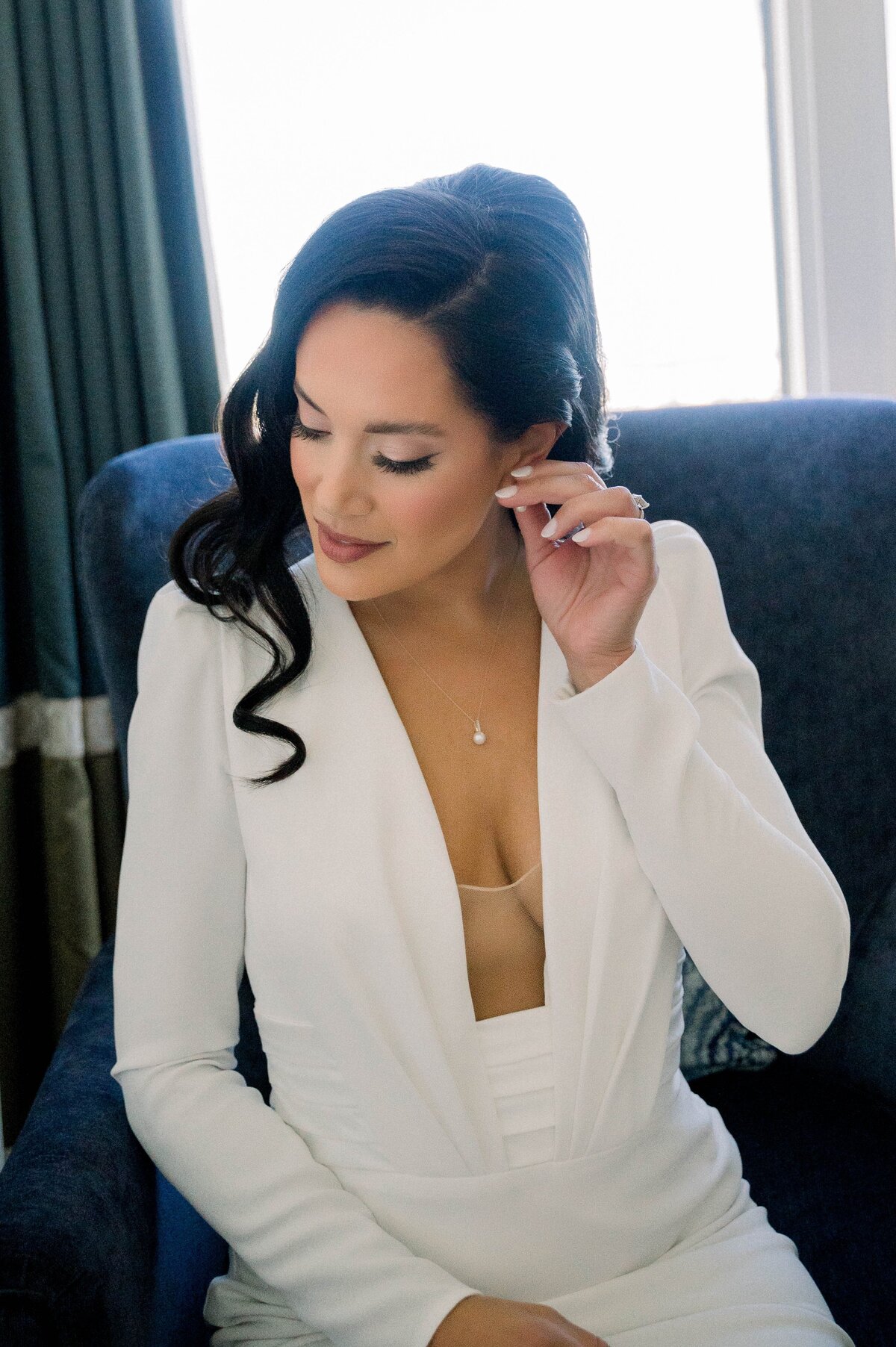 bride in a wedding dress putting on earrings