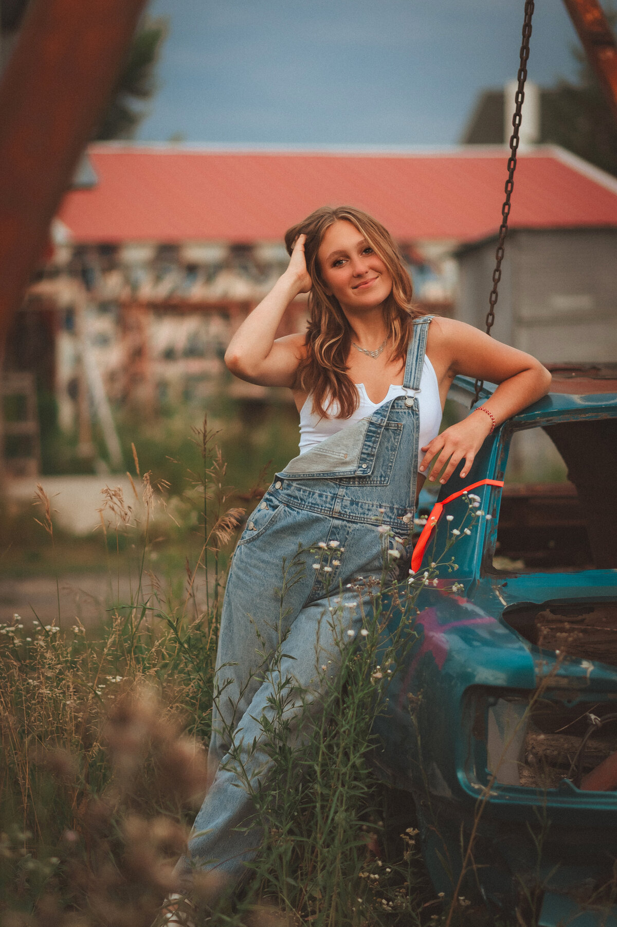 Female senior standing next to a car in a field outside