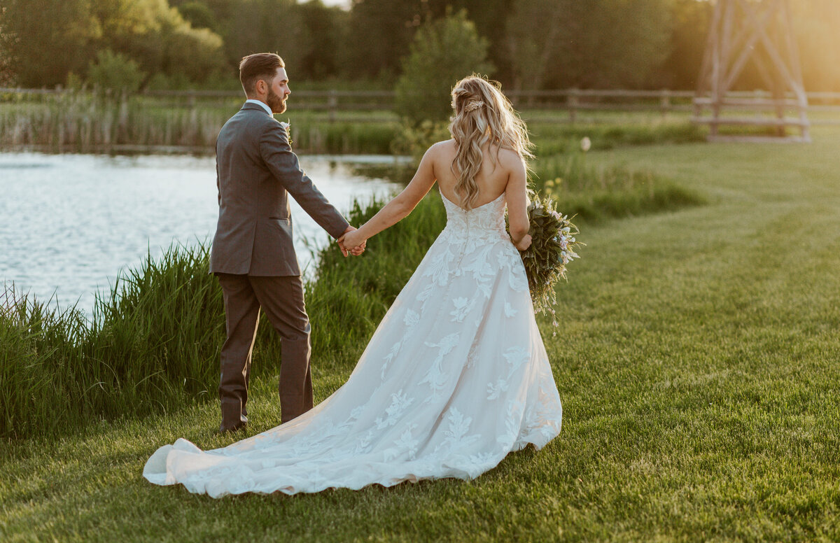 bride and groom holding hands by lake