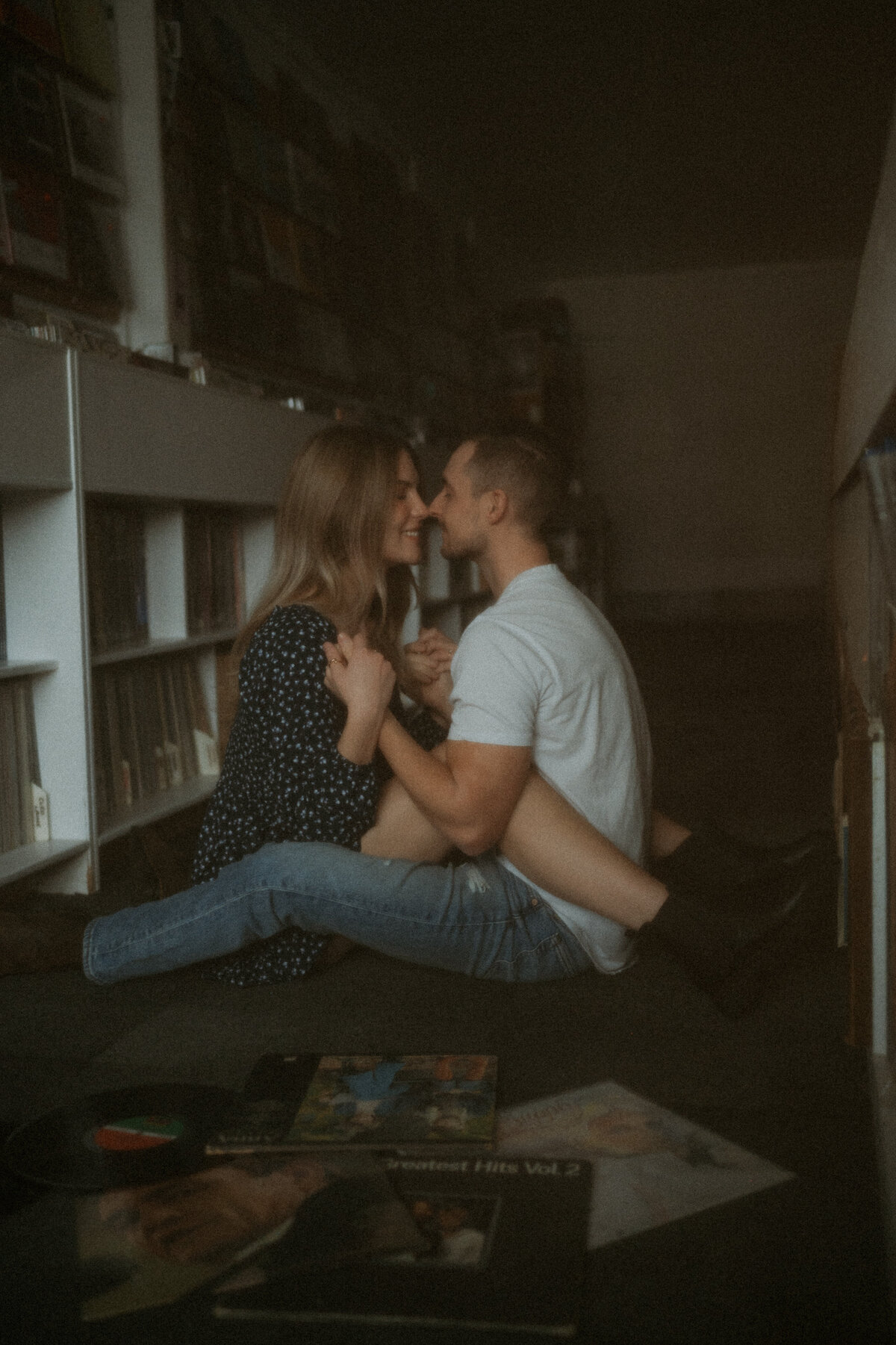 Photo of newly engaged couple cozy in a record store