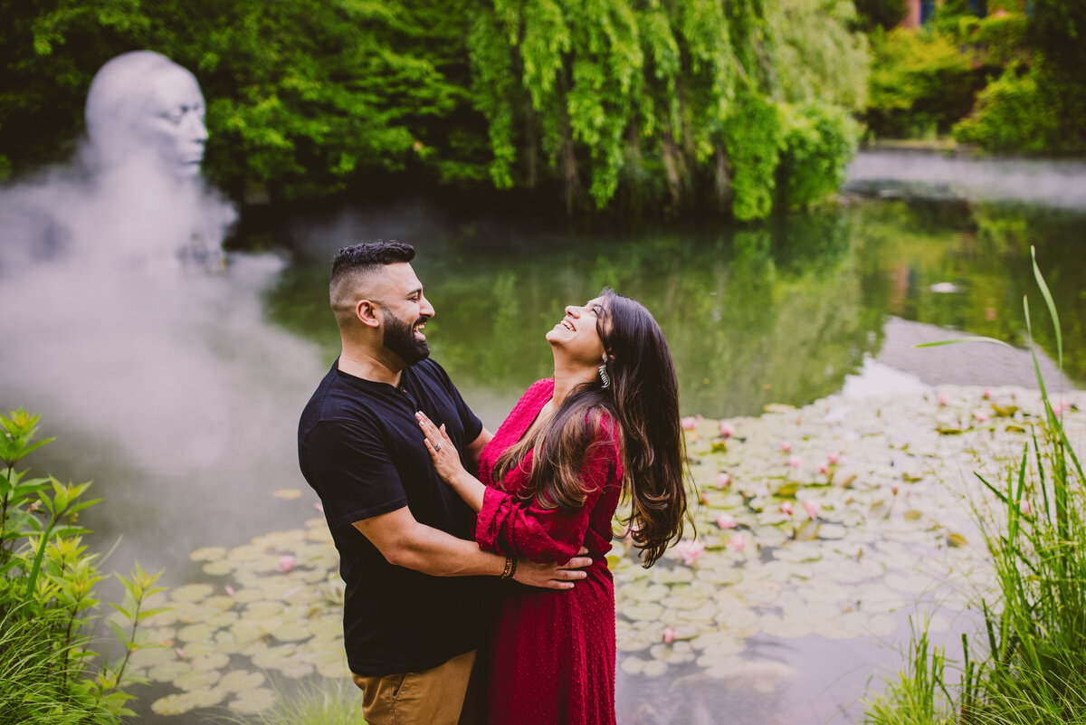 A couple laughing in front of a pond at the grounds for sculpture gardens in nj