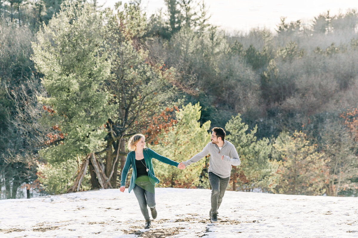 couple holding hands and running up a hill