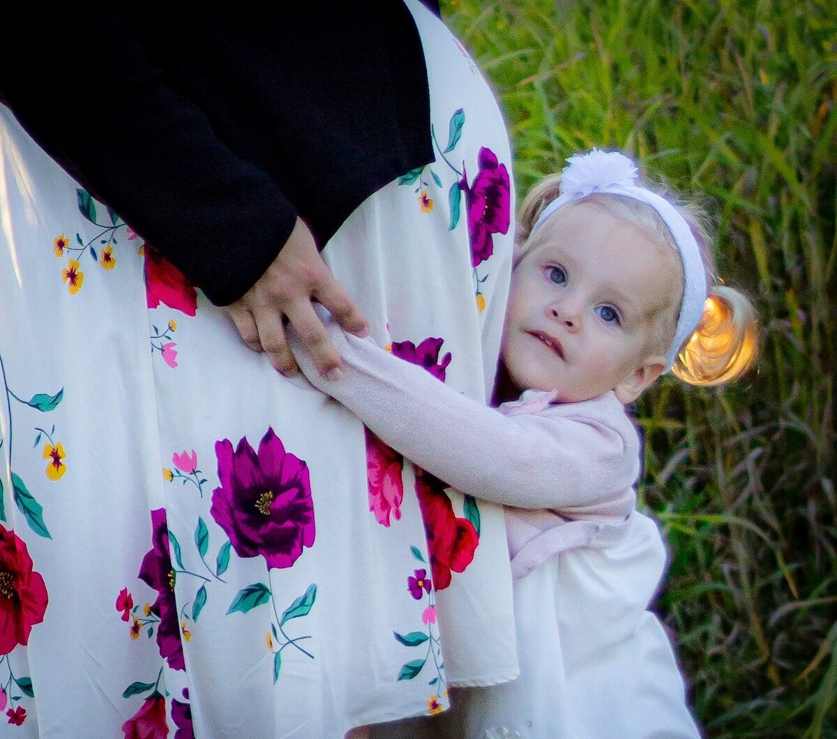 a little girl hugs her moms pregnant belly in a field in Edmonton 