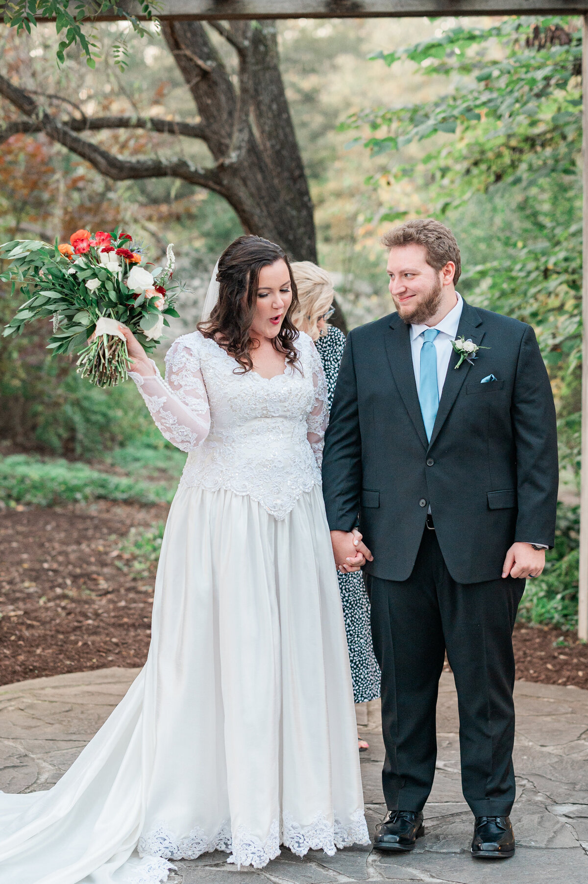 A newlywed couple holding hands and smiling at each other