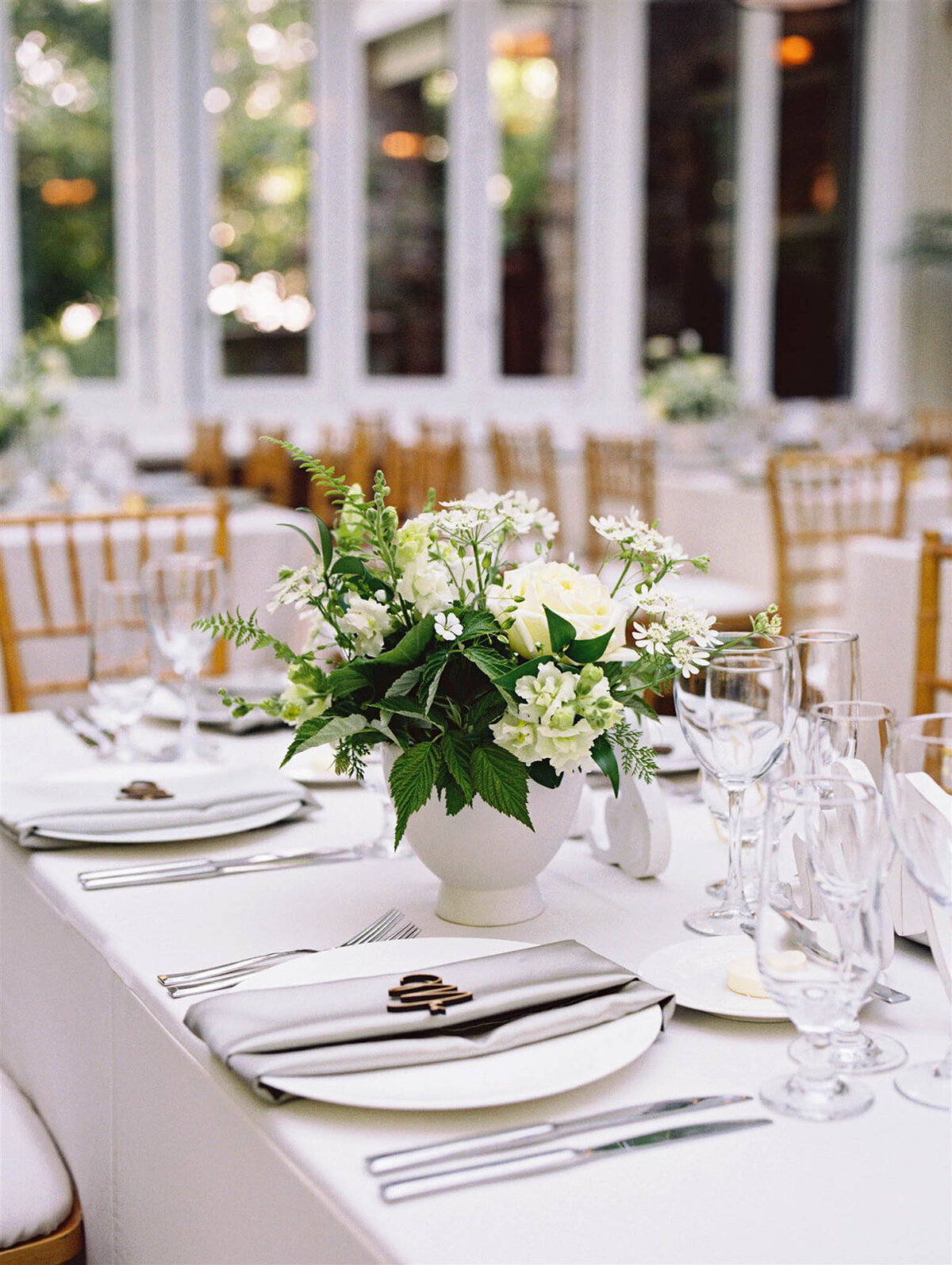 White linens and white florals adorn a table for wedding reception