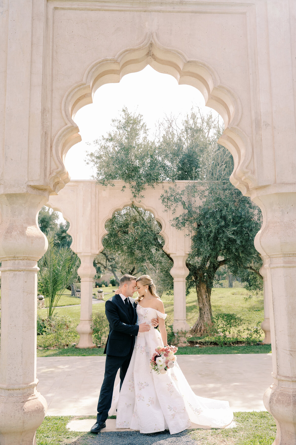 Bride and groom standing in arches at Palais Namaskar Morocco for a destination wedding photographed by Italy photographer