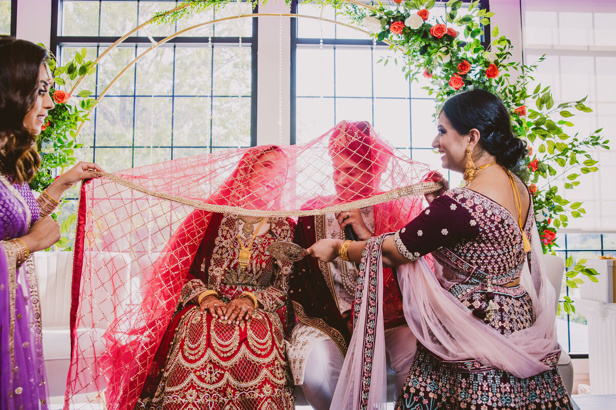bengali bride and groom looking at a mirror together during the traditional mirror ceremony during their muslim wedding