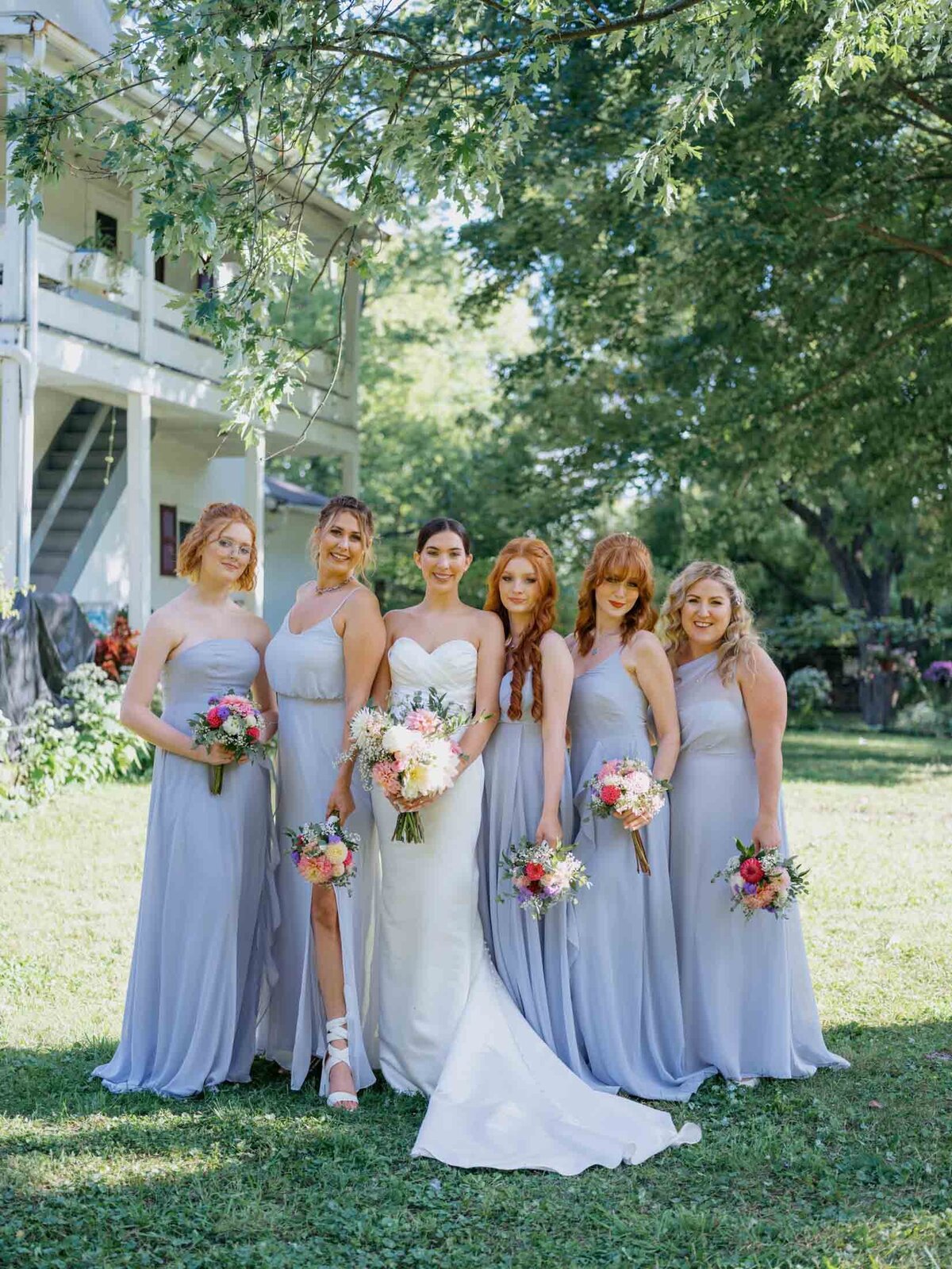 Bride in Maggie Sottero gown with bridesmaids in blue Birdy Grey dresses.