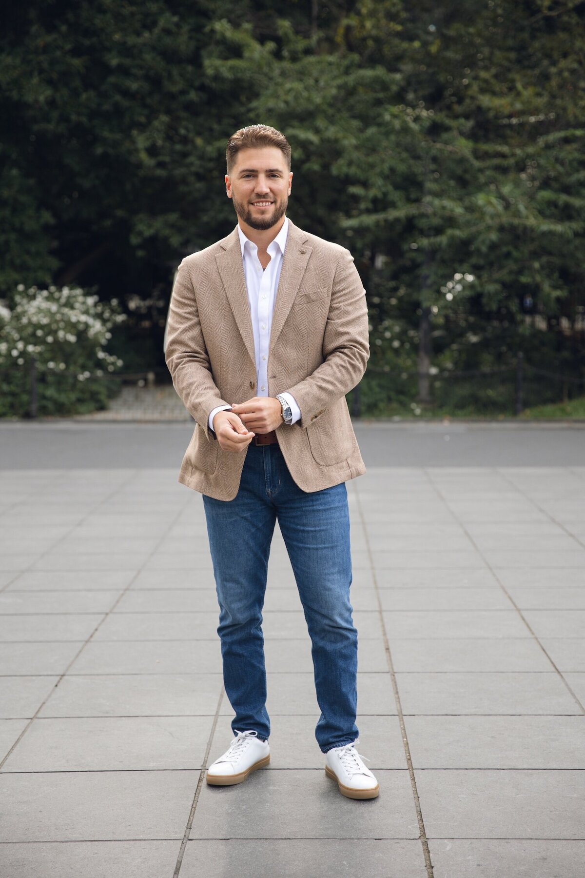 Groom-to-be smiling and standing in Washington Square Park before the proposal.