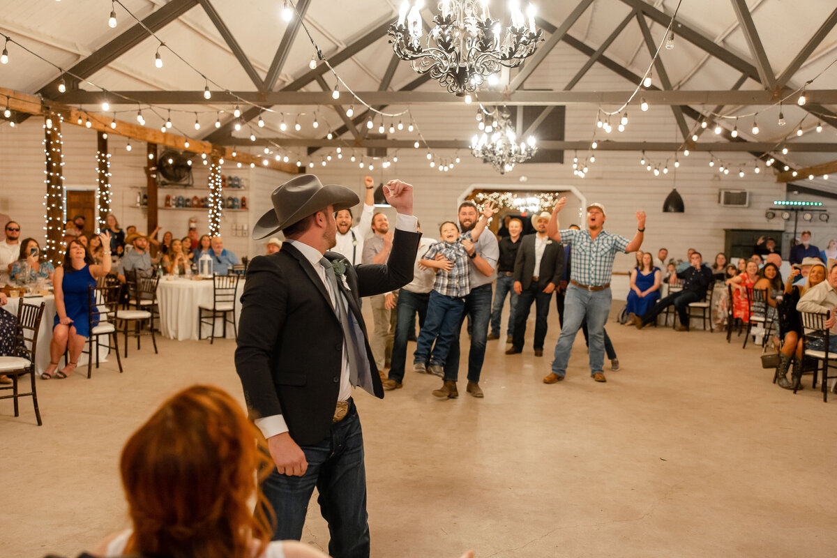groom in cowboy hat tosses garter in Boerne Texas wedding