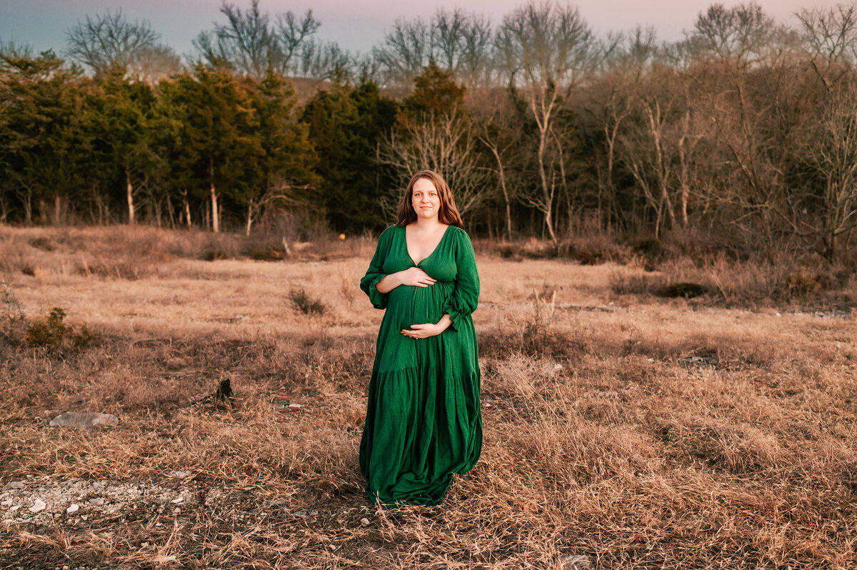 Springfield MO maternity photography of pregnant mom in field in the winter holding baby bump