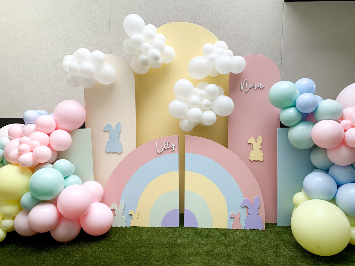Pastel colored arch backdrop design with rainbows, bunnies, and balloons