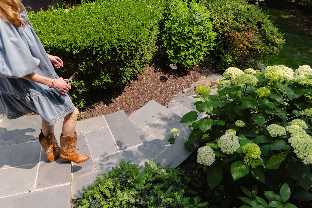 Woman walking down stone hardscaping stairs in professionally landscaped yard