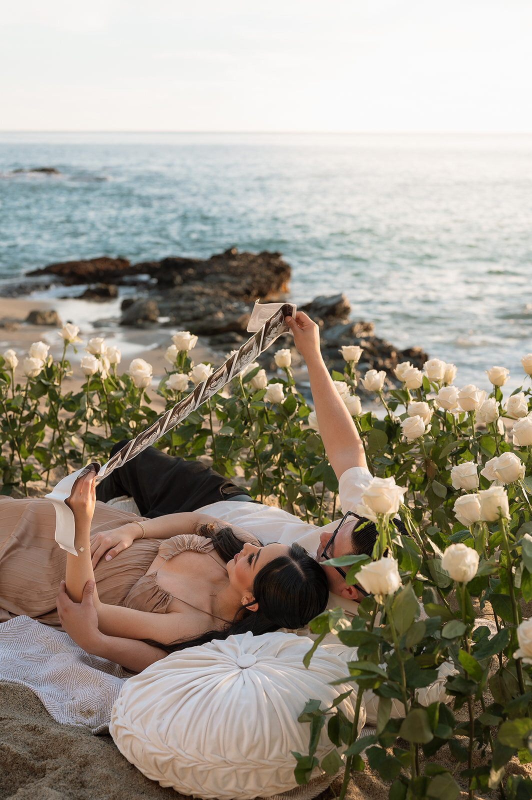 photo of mom and dad laying in a bed of flowers oceanside during family photos