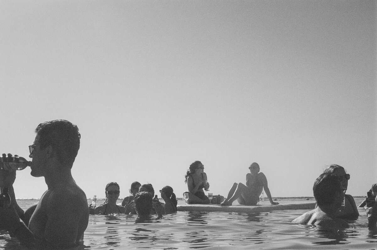 Grainy black and white film image of people floating on and submerged in the ocean at a wedding at Round Hill Resort in Jamaica